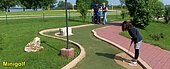 Der Minigolfplatz am Altmühlsee bietet Spaß für die ganze Familie. Gerade ist ein kleines Mädchen auf dem grünen platz dabei den Schläger zu schwingen.