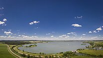 Der Altmühlsee bei Gunzenhausen bei hellblauem Himmel von oben komplett zu sehen.