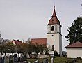 Kirche mit Turm und rotem Dach in einem Friedhof mit Grabsteinen und B&auml;umen bei bew&ouml;lktem Himmel.